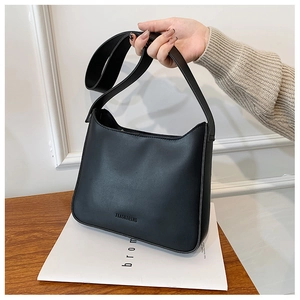 Close-up of black leather crescent underarm bag with debossed logo and wide strap