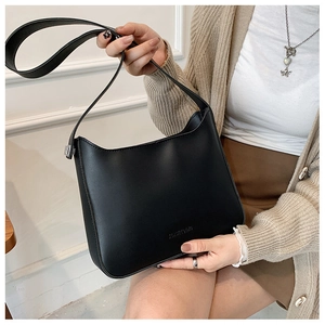 Detail of minimalist black faux leather shoulder bag with embossed brand logo