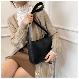 Close-up of minimalist black leather underarm bag with adjustable strap and silver buckle