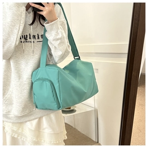 Detail of mint green nylon travel bag showing spacious interior and wide shoulder strap