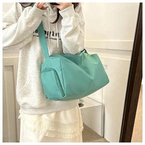 Mirror selfie showing the scale of a mint green nylon travel crossbody bag on a person