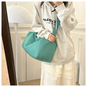 Detail of mint green quilted nylon pillow bag with wide shoulder strap on model