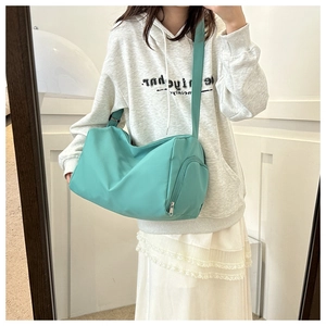 Detail of mint green waterproof nylon gym bag with side pocket shown on a model