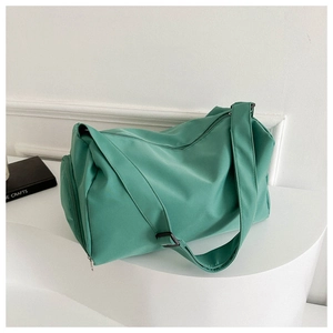 Green nylon travel bag with dual zippers and adjustable strap on a white display stand