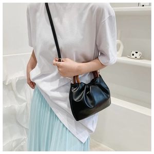 Close-up of black ruched cloud bag with round wooden handles and long shoulder strap
