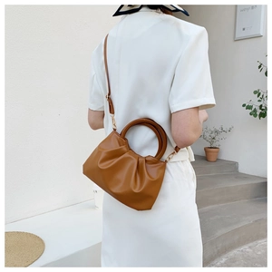 Detail of caramel brown ruched cloud bag with circular handles and a long shoulder strap