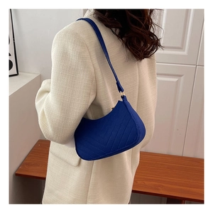 Detail of navy blue quilted crescent shoulder bag styled with beige waffle texture blazer