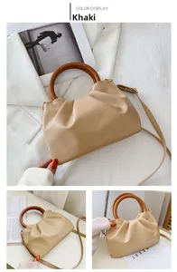 Detail view of khaki cloud pleated mini bag featuring a unique wooden ring handle