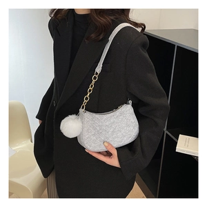 Detail of light gray crescent felt bag with V-quilted texture and fluffy white pompom