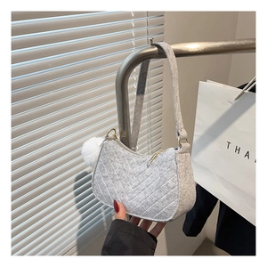 Detail of gray felt shoulder bag featuring V-quilted stitching and white fur ball charm