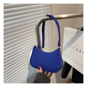 Detail of royal blue suede underarm bag featuring V-shaped quilting and gold hardware