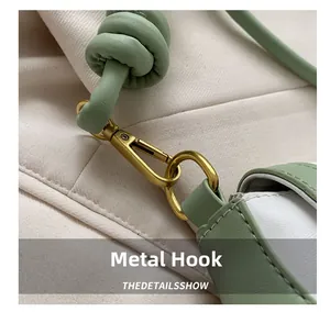 Close-up of golden hardware hook and leather knotted strap on a baguette shoulder bag