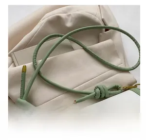 Close-up of mint green and white leather bag with gold buckle and knotted strap