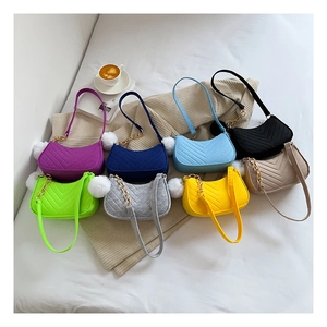 Flat lay of colorful quilted crescent bags with gold chain details and fur ball charms