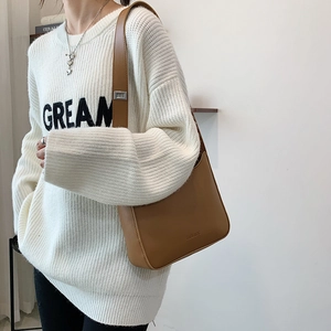 Minimalist brown faux leather underarm shoulder bag with matte texture and cream sweater