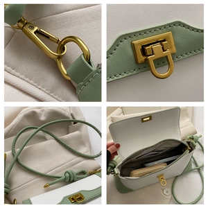 Detail view of contrast green and white crossbody bag featuring gold rotating metal clasp