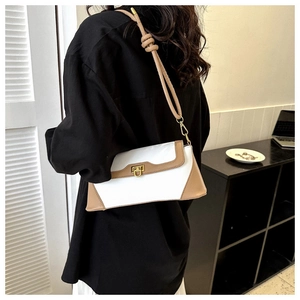 Close-up of beige and brown leather shoulder bag with metal lock and knotted strap details