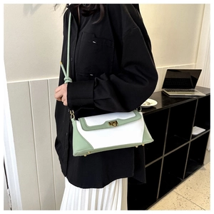 Detail of cream and green baguette bag with gold buckle and knot strap design
