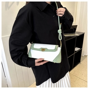 White baguette bag with green trim shown on shoulder of a model in black shirt