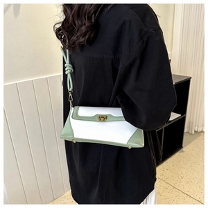 Detail view of mint green and white color-block baguette bag with golden turn-lock