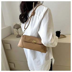 Detail of khaki leather baguette bag featuring a gold clasp and knotted shoulder strap