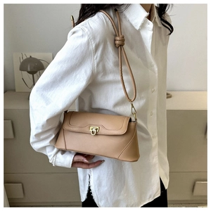 Detail of light brown retro baguette bag with golden U-shaped buckle and knotted strap