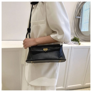 Classic black leather underarm bag with gold lock and protective bottom studs on model
