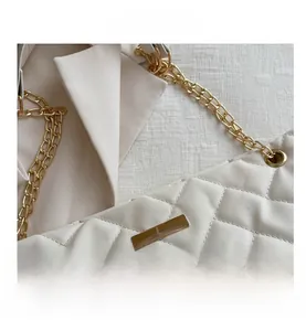 Nahaufnahme der beigen Stepptasche mit goldener Schnalle und Kettenriemendetails