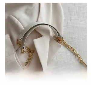 Detail des gepolsterten Griffs und der goldenen Kette an der beigefarbenen Stepptasche