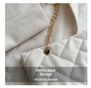 Nahaufnahme der gesteppten beigen Ledertasche mit Ösendesign und Goldkettendetails
