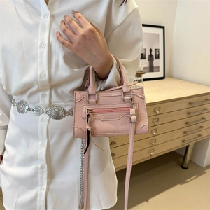 Mini sac carré en cuir mat rose avec poignée et bandoulière porté par un mannequin