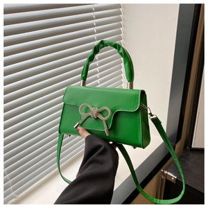 Detail der grünen Kunstlederhandtasche mit Strassschleife und gerafftem Griff