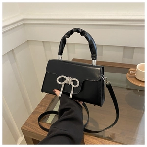 Detail der schwarzen Handtasche mit glitzernder Strassschleife und gerafftem Griff