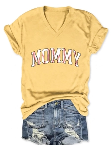 Flat lay of yellow V-neck T-shirt with MOMMY baseball print and ripped denim shorts