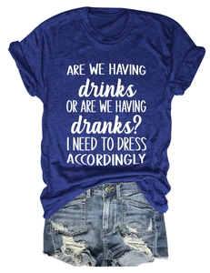Flat lay of women's casual T-shirt with 'drinks' slogan and distressed denim shorts