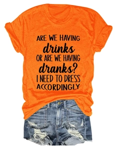 Flat lay of an orange crew neck t-shirt with a humorous black typography slogan and denim shorts