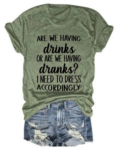 Flat lay of a sage green crew neck slogan t-shirt paired with distressed denim shorts