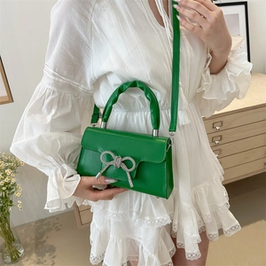 Schicke grüne Lacklederhandtasche mit funkelnder silberner Strass-Schleife und Kette