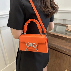 Strukturierte hellorange Umhängetasche mit Strass-Schleife und silbernem Kettenriemen