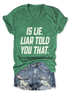 Flat lay of a green V-neck T-shirt with 'IS LIE' text and distressed denim shorts