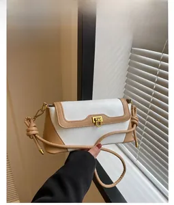 Detail of the white and khaki contrast handbag with gold twist lock and knotted strap