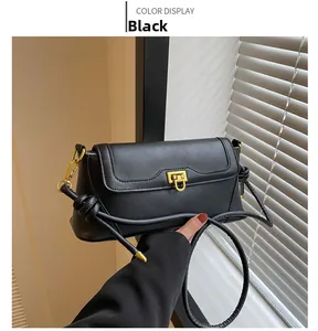 Detail of black crossbody bag featuring matte leather texture and a gold metal buckle
