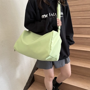 Light green nylon travel pillow bag with wide shoulder strap worn by female model