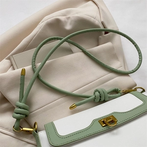 Detail of sage green knotted shoulder strap and gold twist lock on bicolour crossbody bag