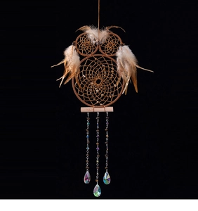 Detailed view of handmade owl dreamcatcher with brown feathers and crystal pendants