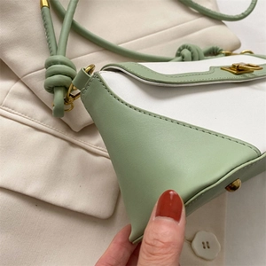 Detailed close-up of mint green leather crossbody bag with knot strap and gold hardware