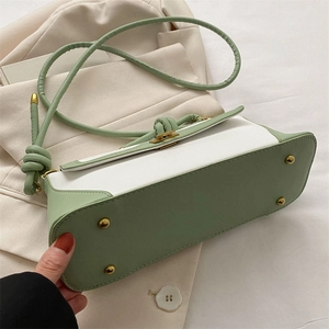 Close-up of the bottom of a green and white leather bag with gold protective feet