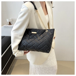 Nahaufnahme der schwarzen geflochtenen PU-Tasche mit Goldkette und Metallplakette
