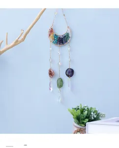 Detail of moon-shaped crystal suncatcher with gold metal frame and colorful stones
