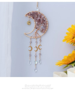 Detail of moon-shaped crystal suncatcher with pink tree of life and metal drops